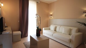 A modern living room with a white sofa, a coffee table, a TV, and a plant.