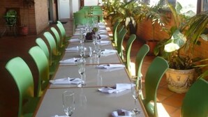 A long dining table set with chairs, glassware, and napkins, surrounded by potted plants and a brick wall. - Hotel Torre del Prado (Barranquilla)