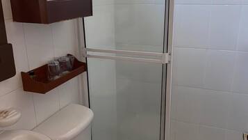 A bathroom with a toilet, sink, and glass-enclosed shower stall.