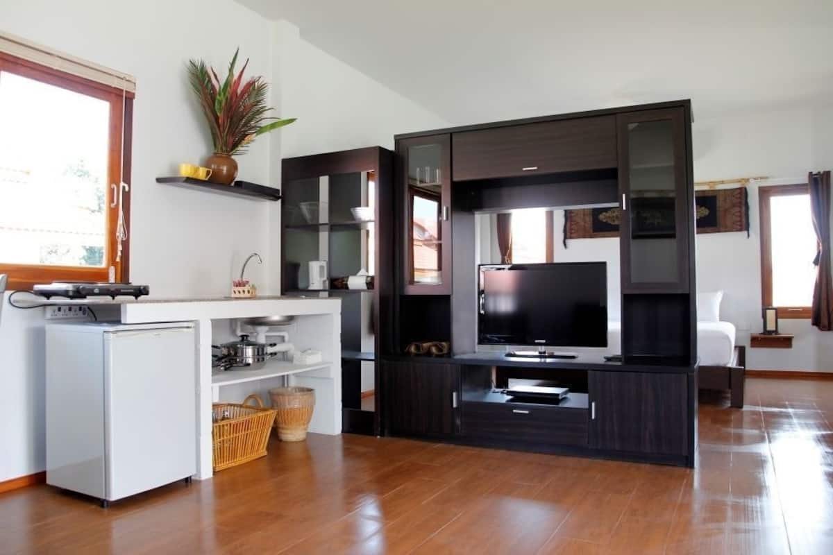 A compact living space with a kitchenette, a flat-screen TV, and a dining area.