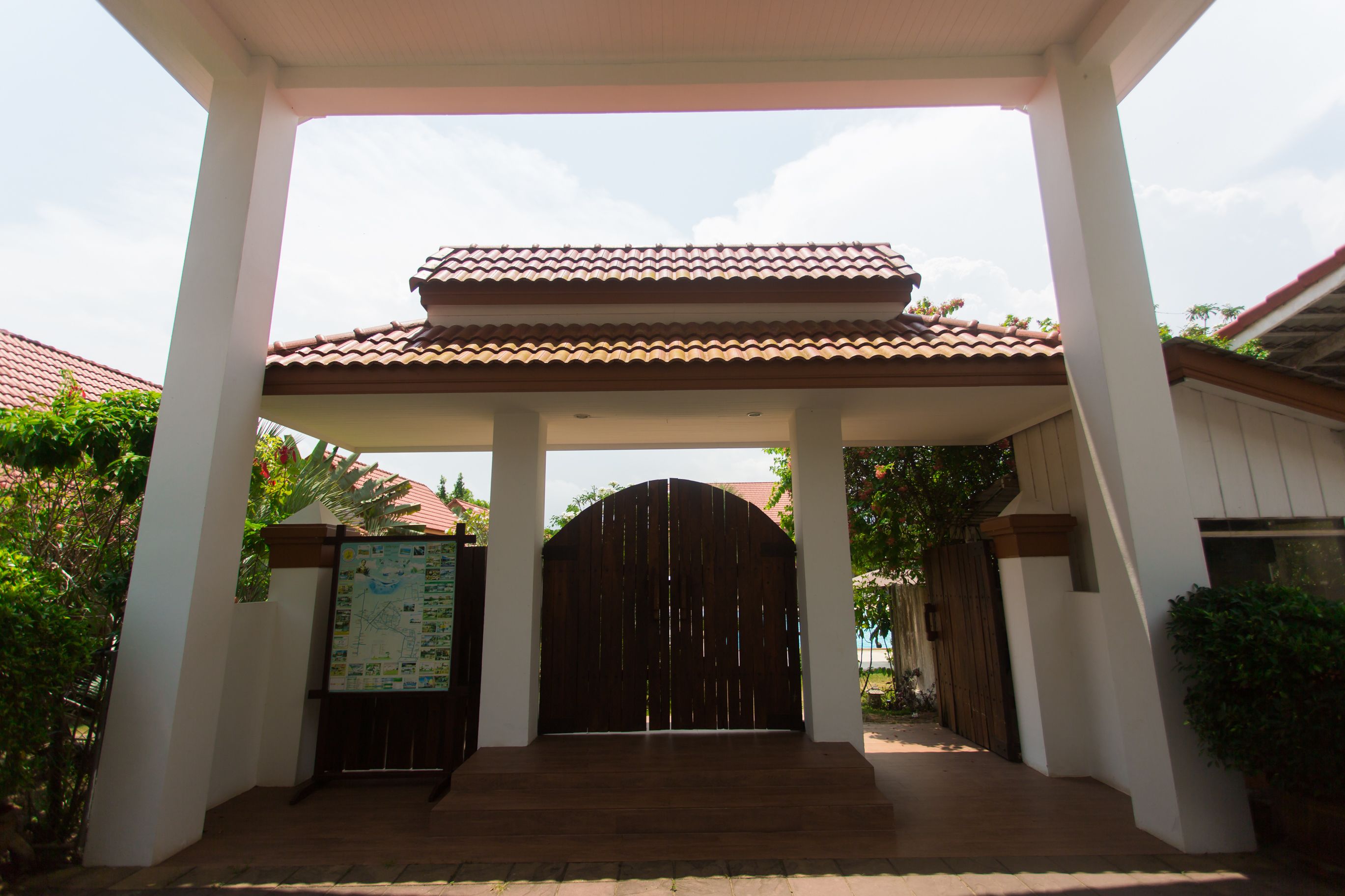 A covered entrance with a tiled roof, a wooden gate, and a map on the wall.