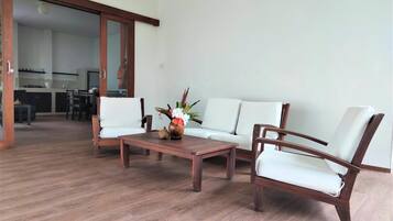 A modern living room with a wooden coffee table, two white cushioned chairs, and a sofa.