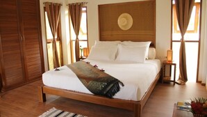 A neatly made bed with a wooden frame, a woven headboard, and a decorative pillow. - Armonia Village Resort and Spa (Chumphon)