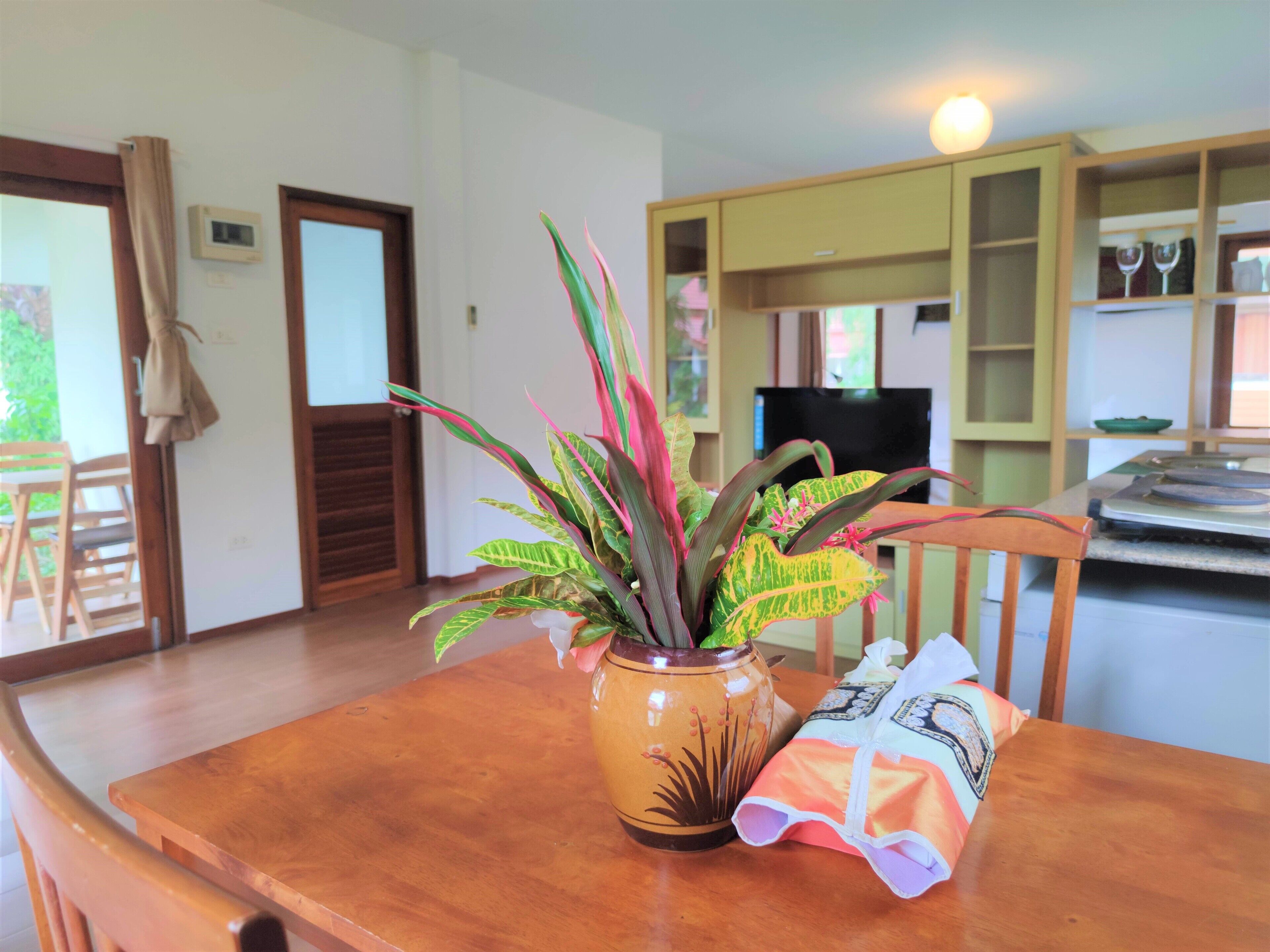 A wooden dining table with a potted plant and a bag of snacks.