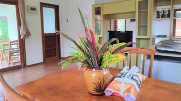 A wooden dining table with a potted plant and a bag of snacks.