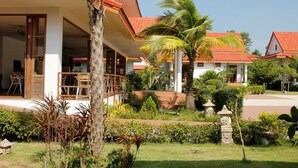 A resort with a covered outdoor area, palm trees, and a well-maintained garden. - Armonia Village Resort and Spa (Chumphon)