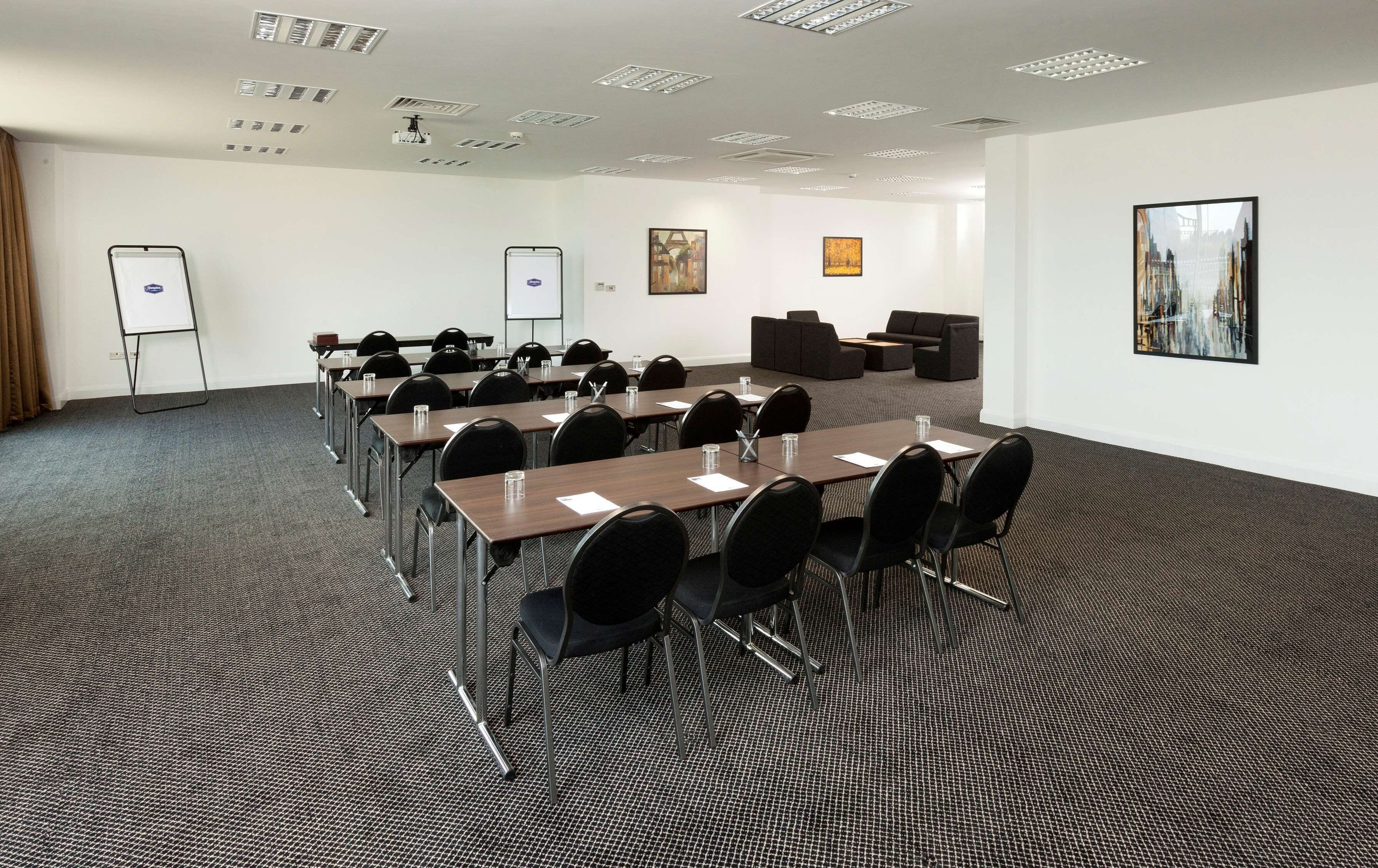 A conference room with multiple tables and chairs, a whiteboard, and a projector.