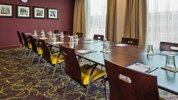 Uma sala de conferências com uma mesa comprida, cadeiras e um relógio na parede.