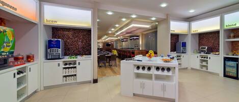 A modern kitchen area with white cabinets, a central island, and various appliances.