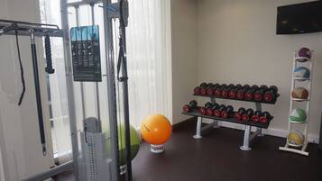 A gym with exercise equipment, dumbbells, and exercise balls.
