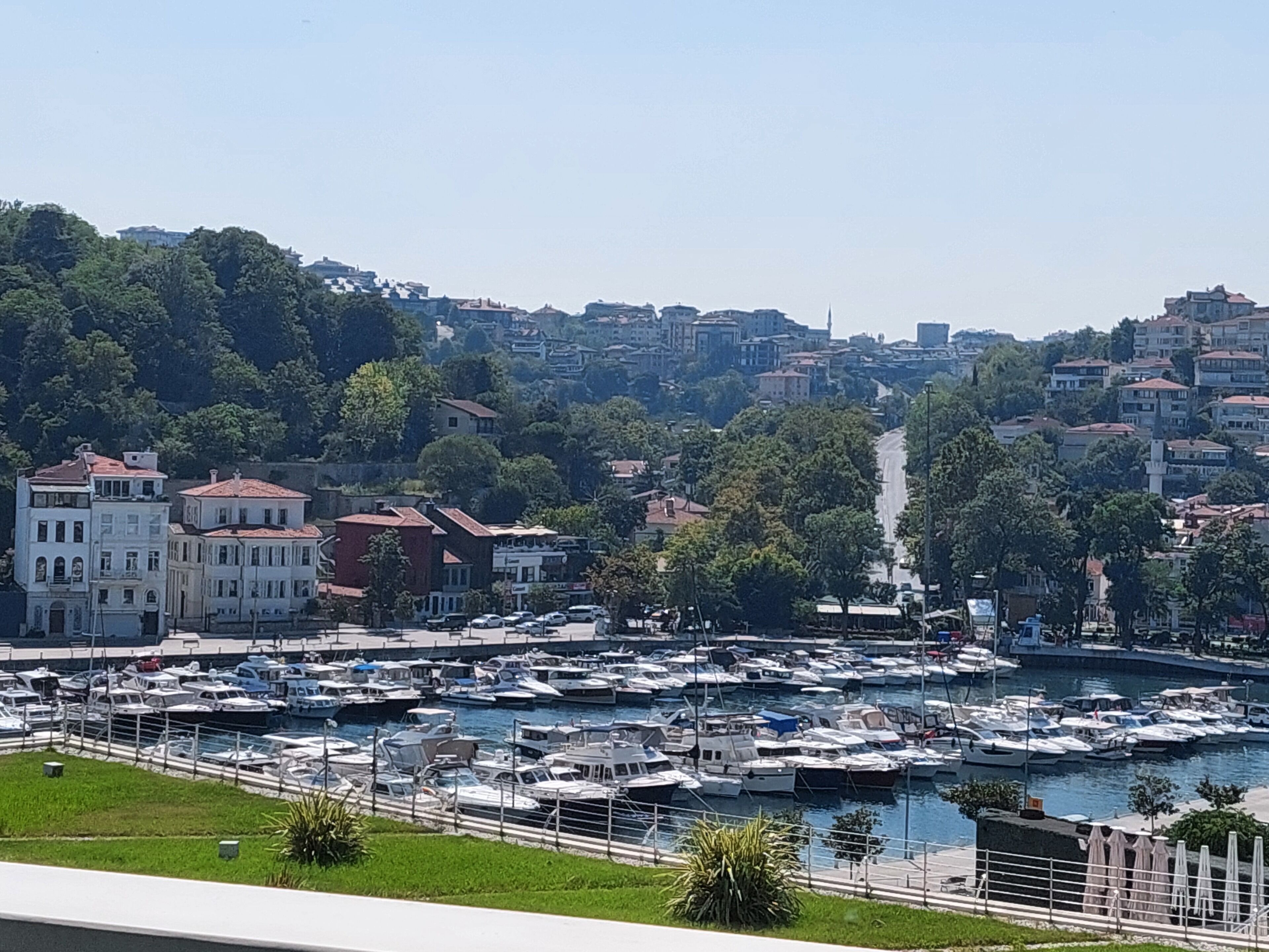 Una marina con imbarcazioni ormeggiate, circondata da edifici e vegetazione.