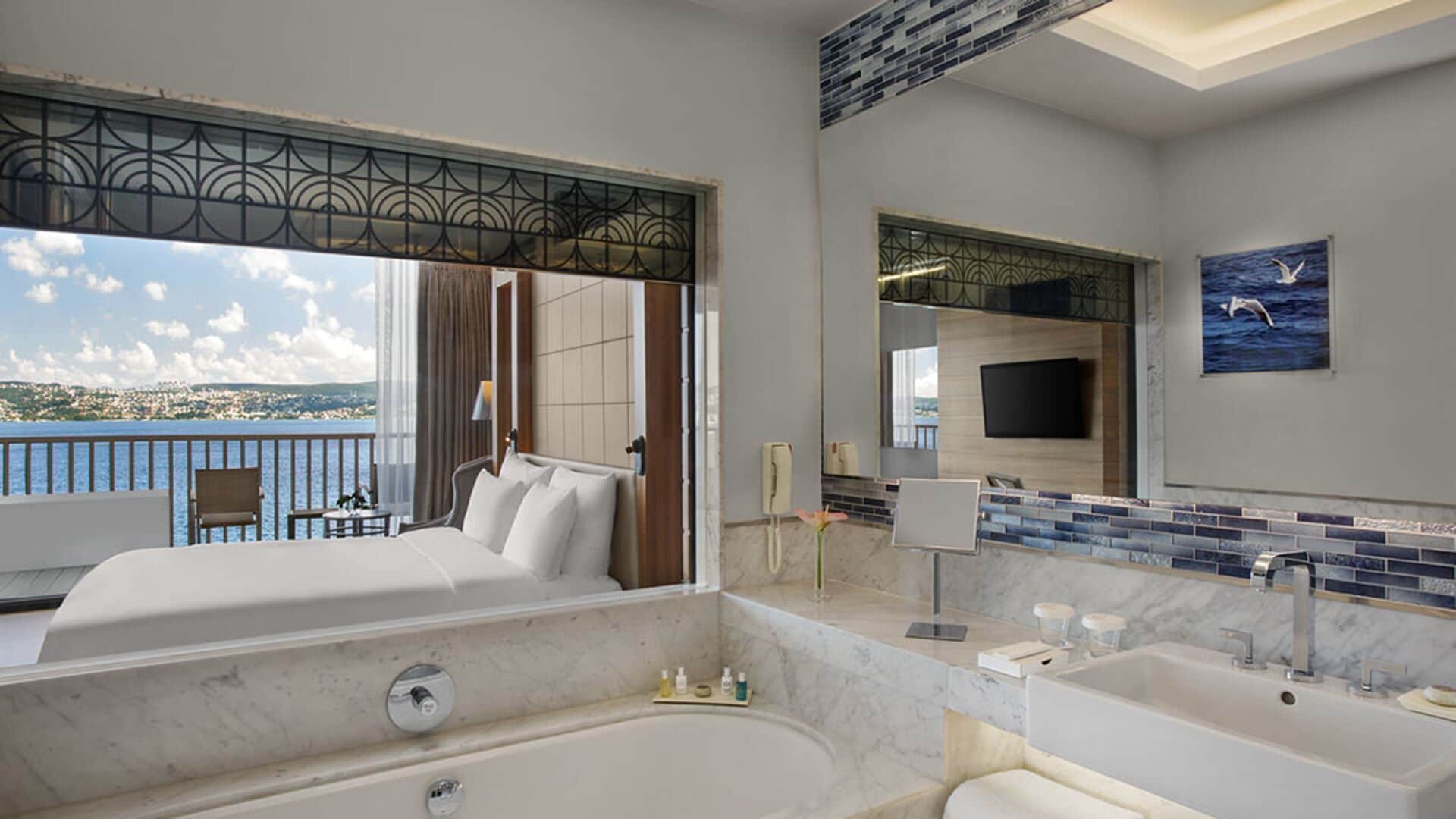 Una camera d'albergo con un letto grande, una vasca da bagno, un comò con uno specchio e vista sul mare.