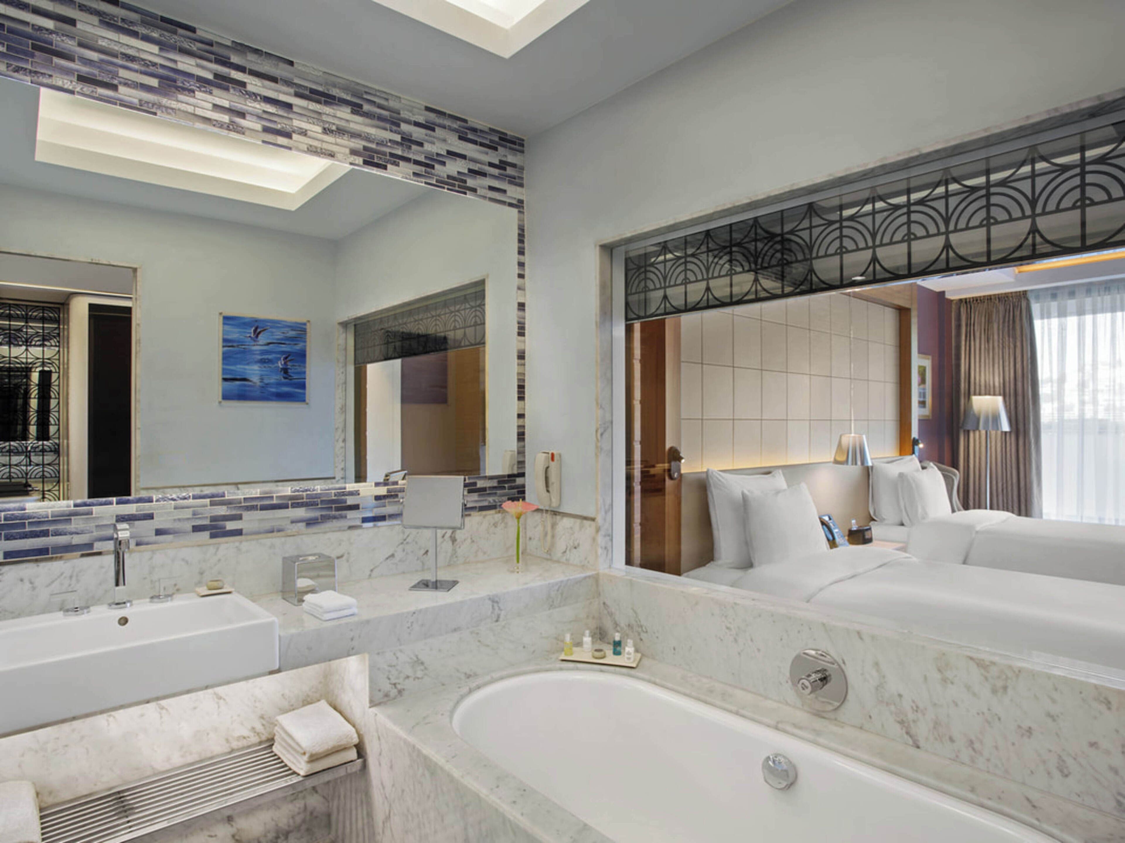 Une salle de bain moderne avec un grand miroir, une baignoire, un meuble-lavabo et un espace douche.
