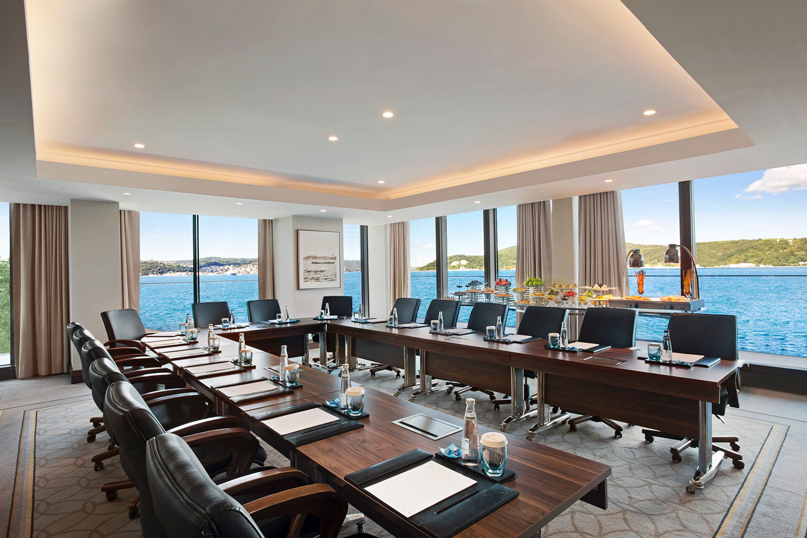 Una sala conferenze con un lungo tavolo, sedie e vista sul mare.