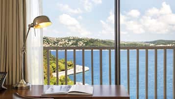 Une pièce avec un bureau, une lampe et une vue sur un paysage côtier.