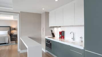 Una cocina moderna con encimera blanca, armarios grises y horno integrado.