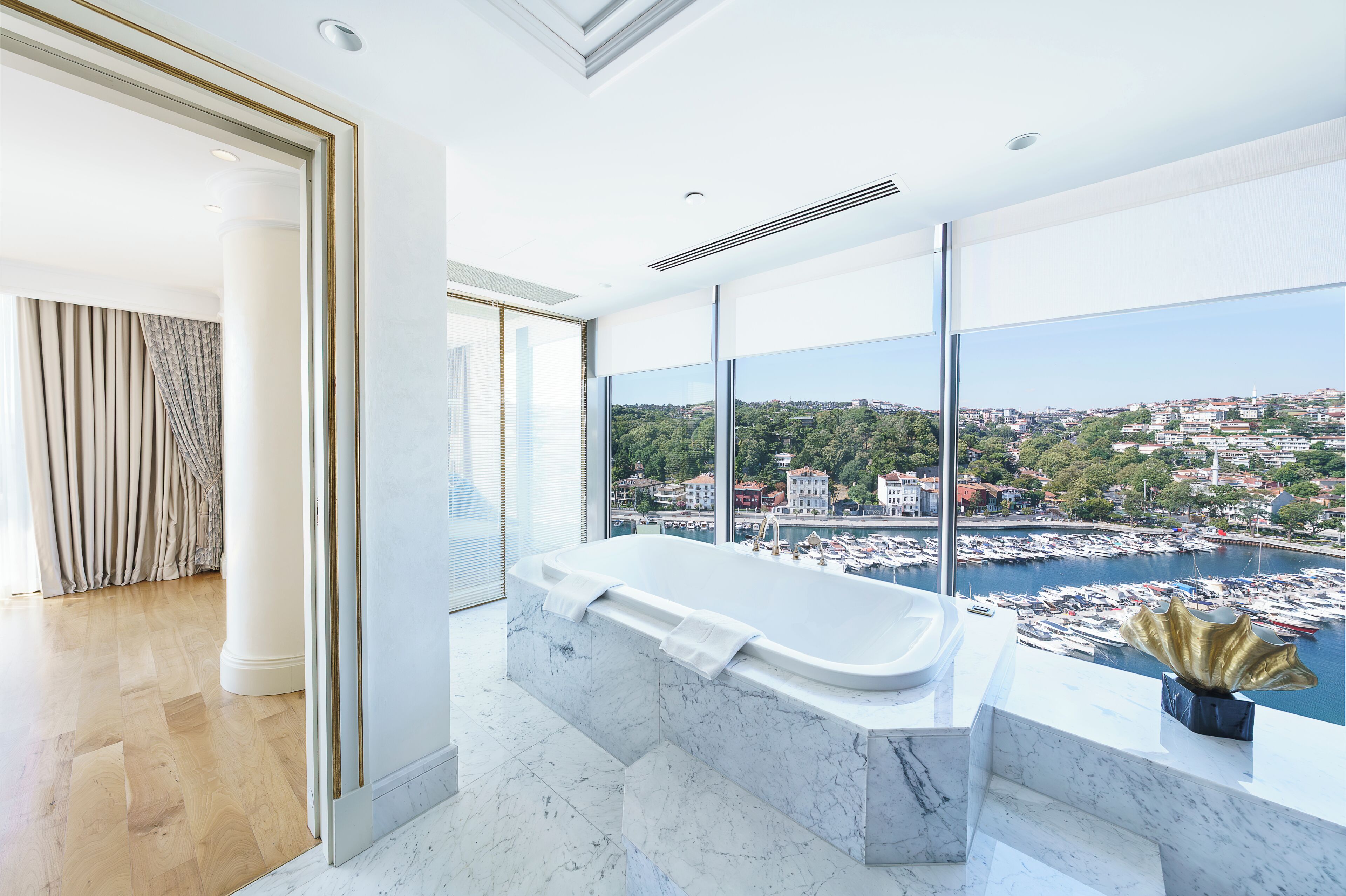 Ein modernes Badezimmer mit einer großen Badewanne, Blick auf einen Hafen und eine Stadtansicht.