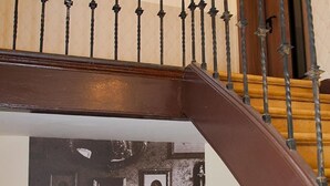 Een houten trap met een metalen leuning en een aan de muur hangend schilderij van een klassiek badkamermeubel.