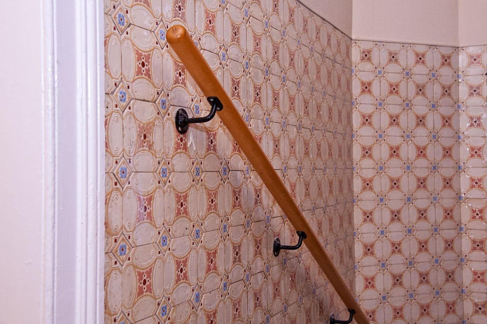Un rincón con un bate de madera apoyado contra una pared con baldosas ornamentadas y un diseño llamativo.