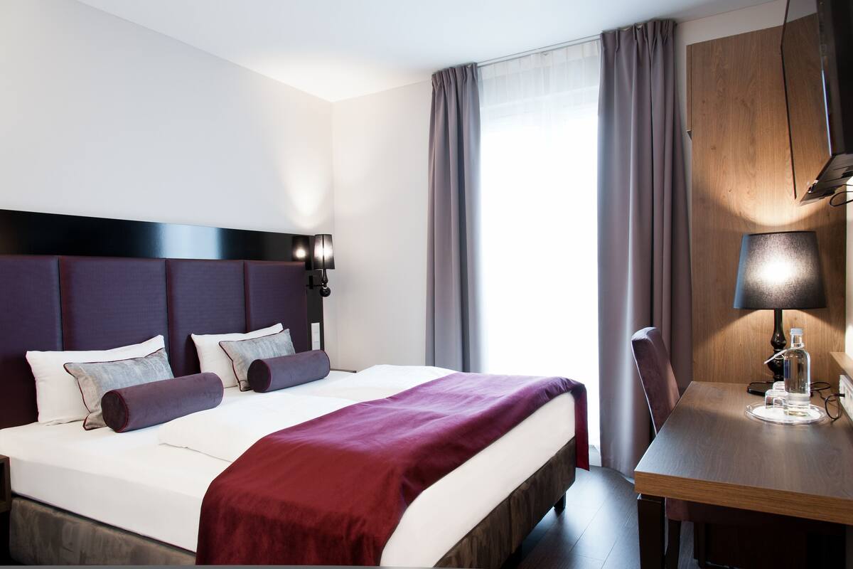 Ein Hotelzimmer mit einem großen Bett, einem Holztisch und einer Lampe.