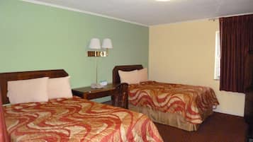 Una habitació d'hotel amb dos llits individuals, una meseta de nit amb una làmpada i una finestra amb cortines.