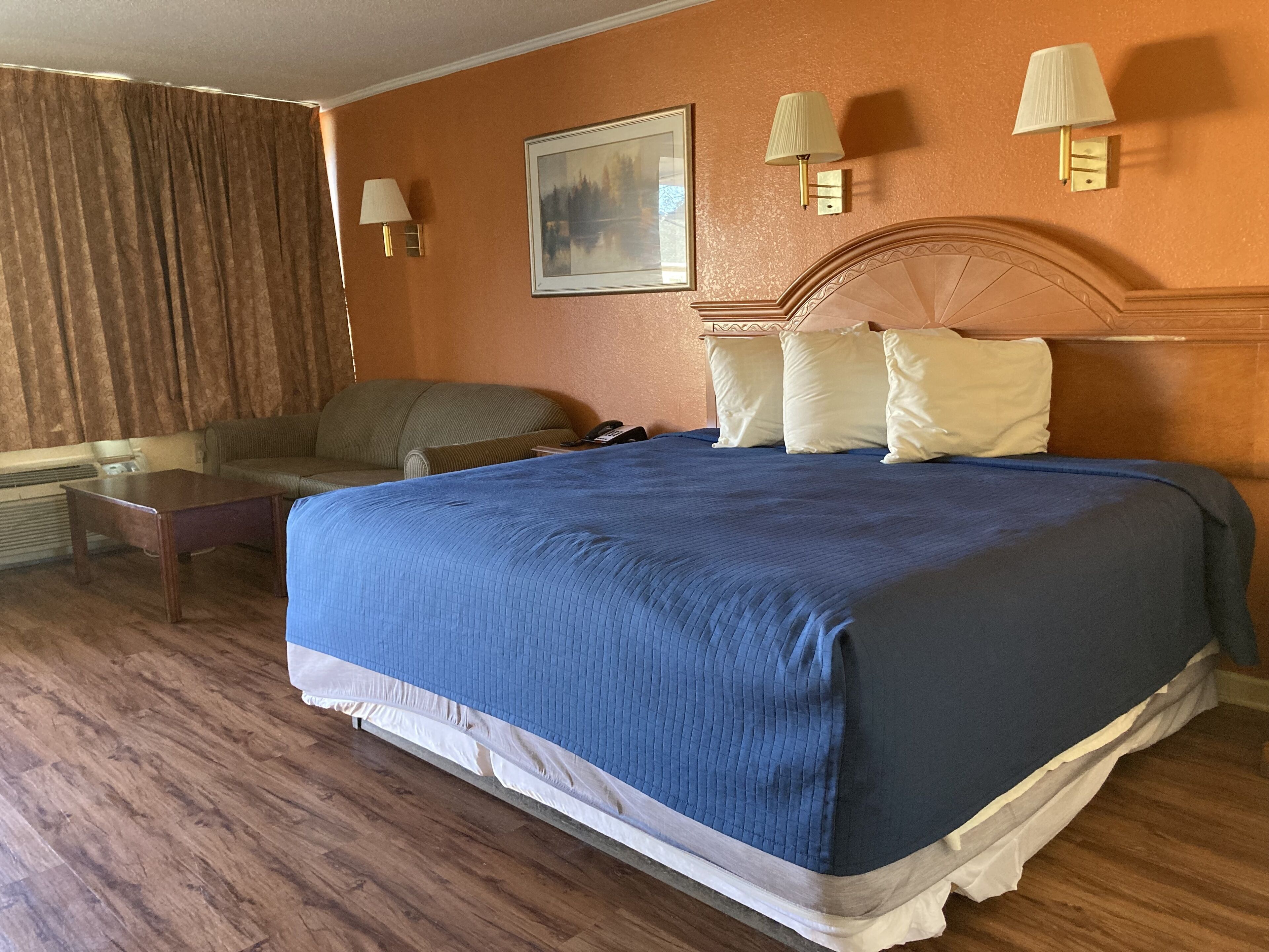 Une chambre d’hôtel avec un grand lit, un canapé, une table et un tableau au mur.