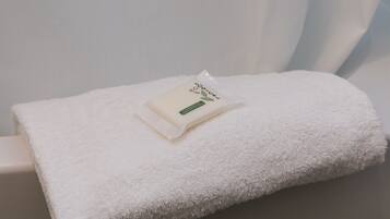 A neatly folded white towel on a white surface with a small package labeled "Eco-Loc" on top.