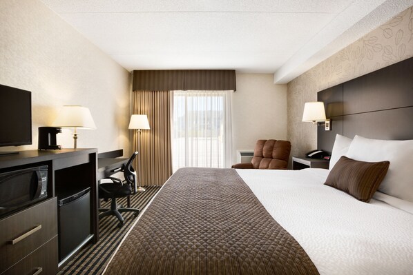 A hotel room with a bed, a desk with a computer, a chair, a TV, and a lamp. - Days Inn by Wyndham Miramichi NB (Miramichi)