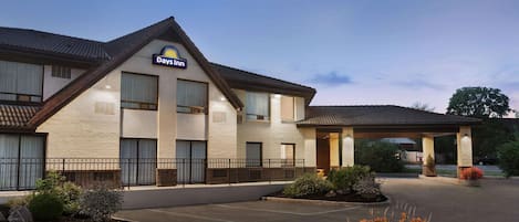 Un hotel Days Inn con un diseño sencillo y moderno, que cuenta con una zona de estacionamiento techada y un acceso con jardines.