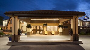 Un hotel Days Inn con un área de estar exterior cubierta, dos sillas y plantas en macetas.
