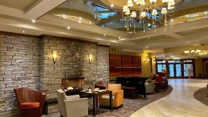 A spacious lobby with a stone wall, a fireplace, a piano, and a chandelier. - An Grianan Hotel (Burt)