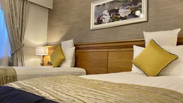 A hotel room with two beds, a wooden headboard, a painting on the wall, and a lamp on the nightstand.