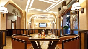 A restaurant with a marble floor, leather chairs, a table with a bottle and glasses, and a TV on the wall. - Best Western Plus Bristol Hotel (Sofia)