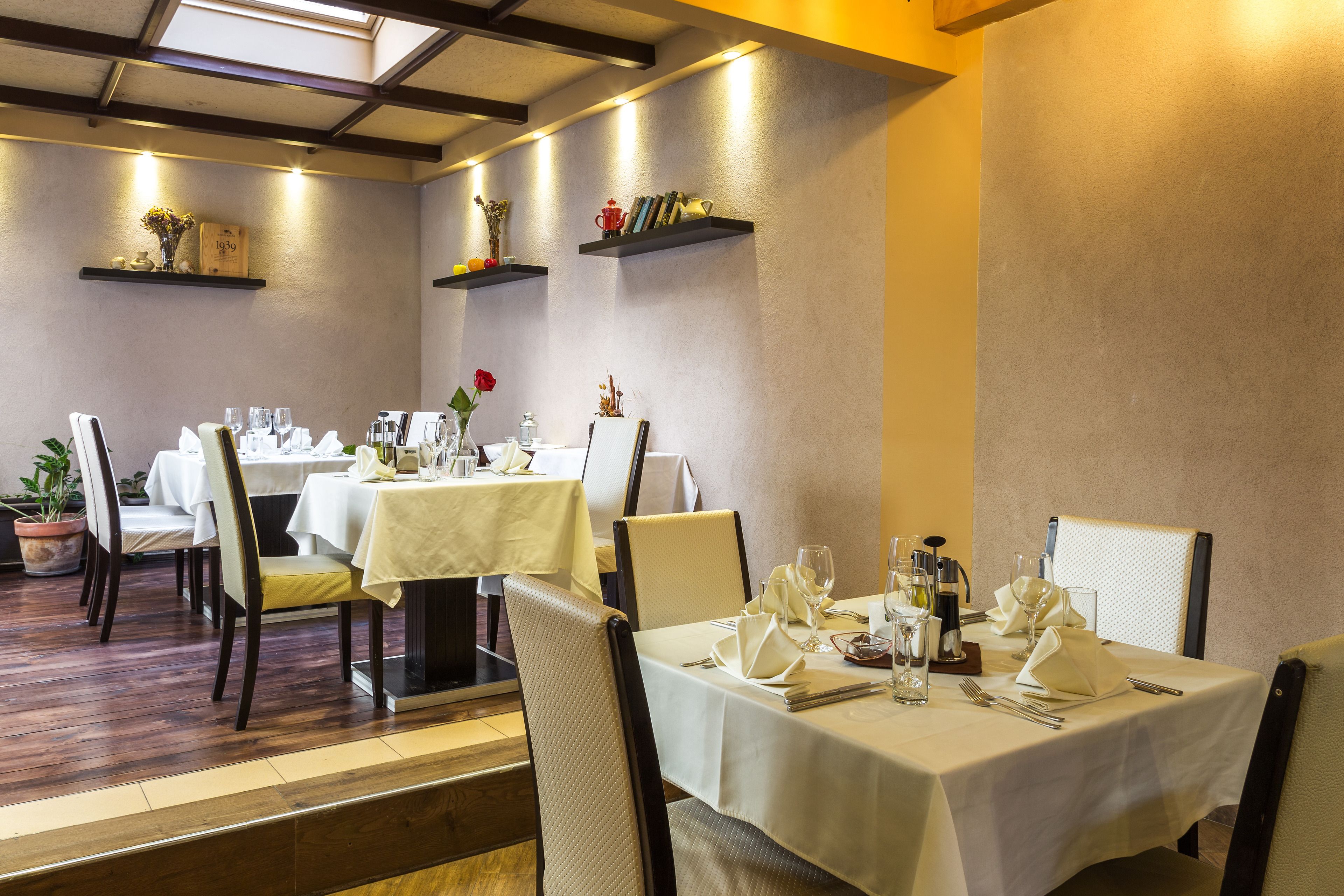 A restaurant with multiple tables set for dining, each with white tablecloths and neatly arranged table settings.