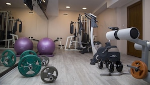 A gym with exercise equipment, including weight plates, a stationary bike, and exercise balls. - Best Western Plus Bristol Hotel (Sofia)