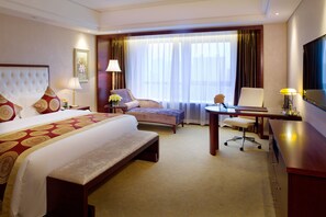 A hotel room with a large bed, a desk, a chair, and a bench. - Howard Johnson Parkview Plaza Erdos (Ordos)