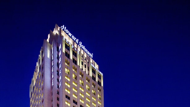 Un grand hôtel, avec une enseigne lumineuse, une vaste entrée et un espace de stationnement.