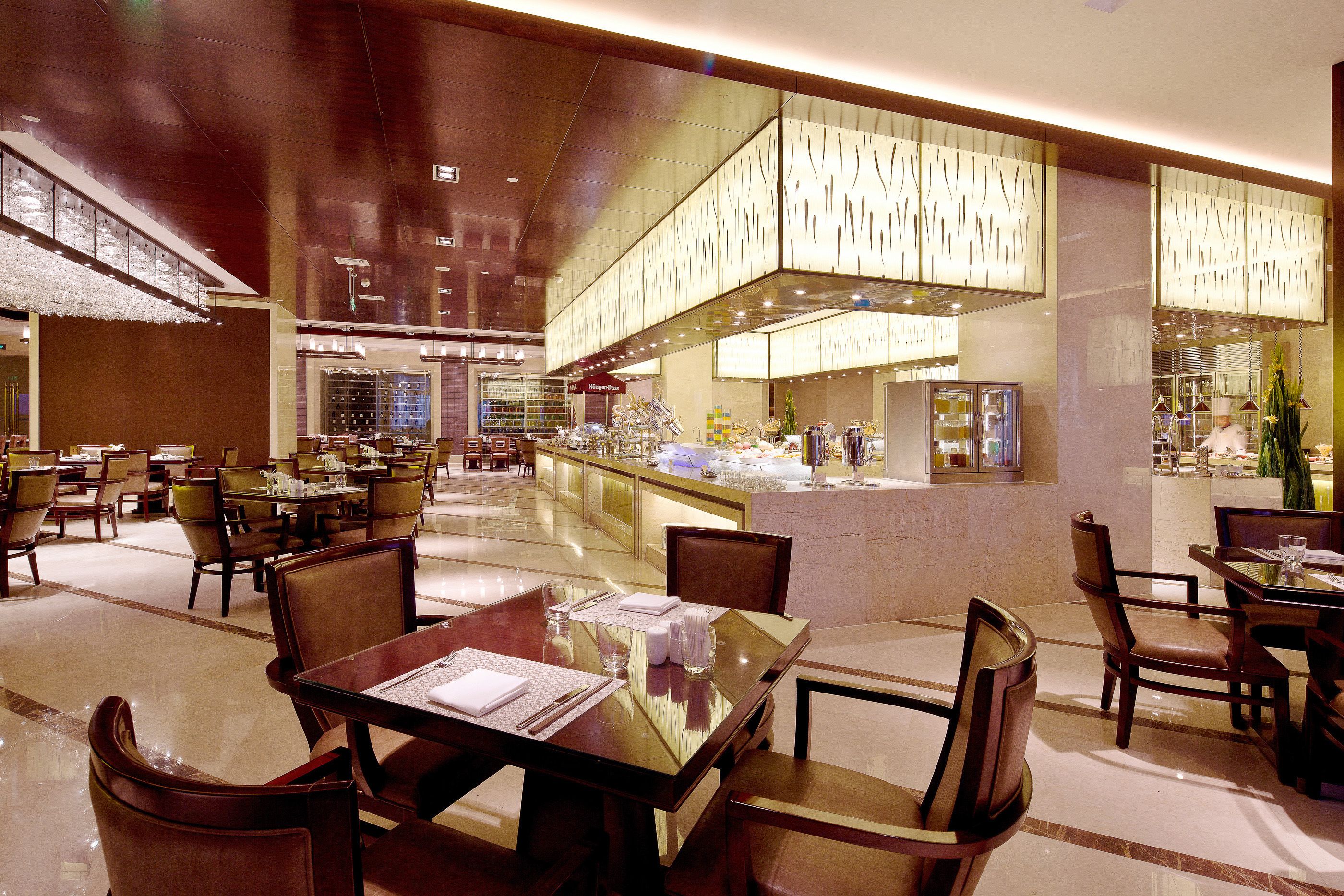 A spacious hotel lobby with multiple dining areas, a central bar, and a well-lit atrium.