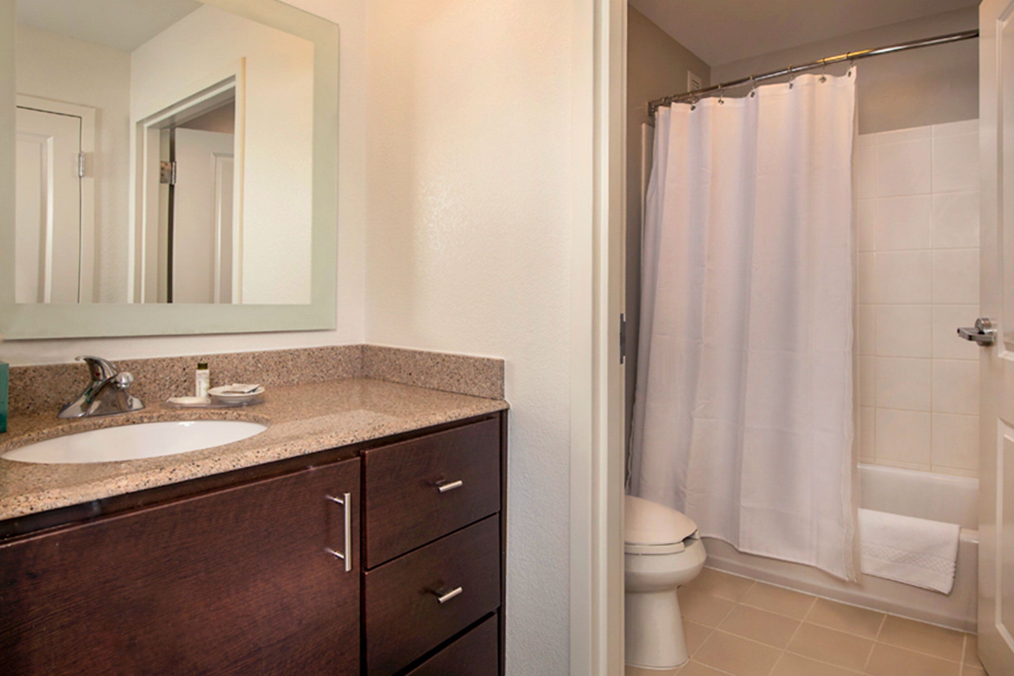 A bathroom with a sink, mirror, and shower curtain.