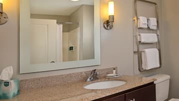 A bathroom with a granite countertop sink, a large mirror, a towel rack, and a toilet.