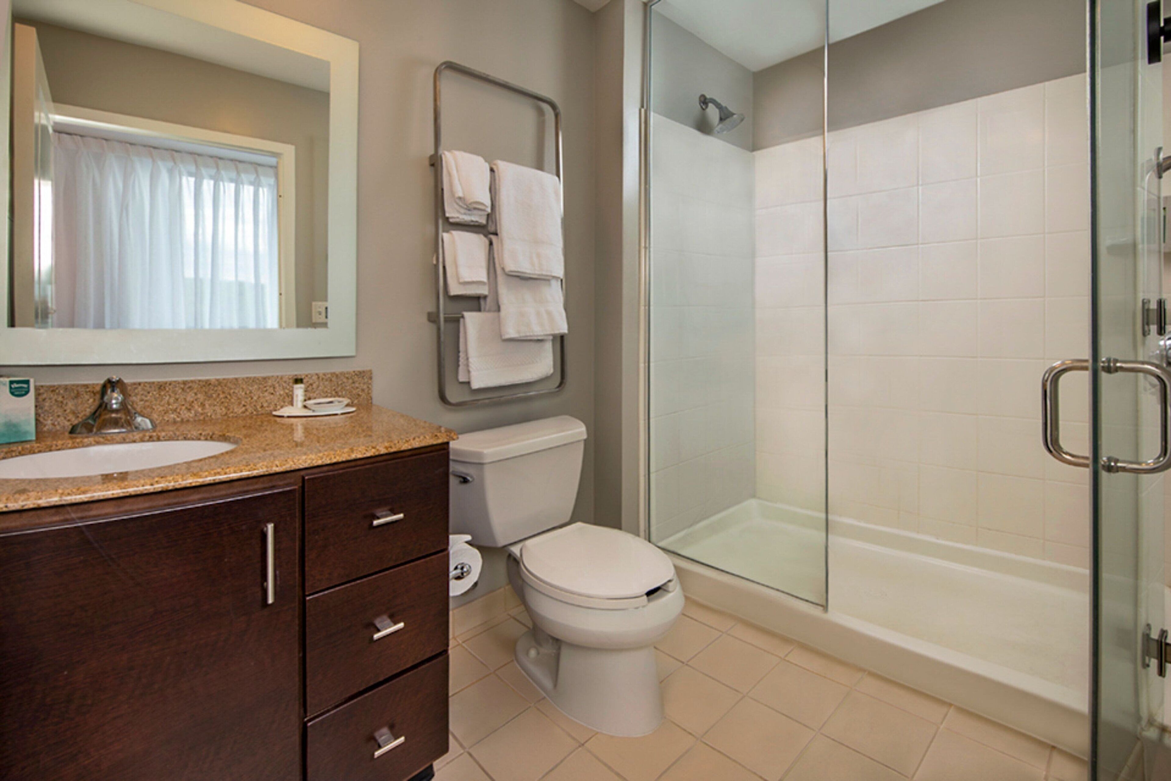 A bathroom with a sink, mirror, toilet, and glass-enclosed shower.