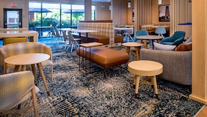 A hotel lobby with seating areas, tables, and a view of the outdoors. - TownePlace Suites by Marriott Frederick (Frederick)
