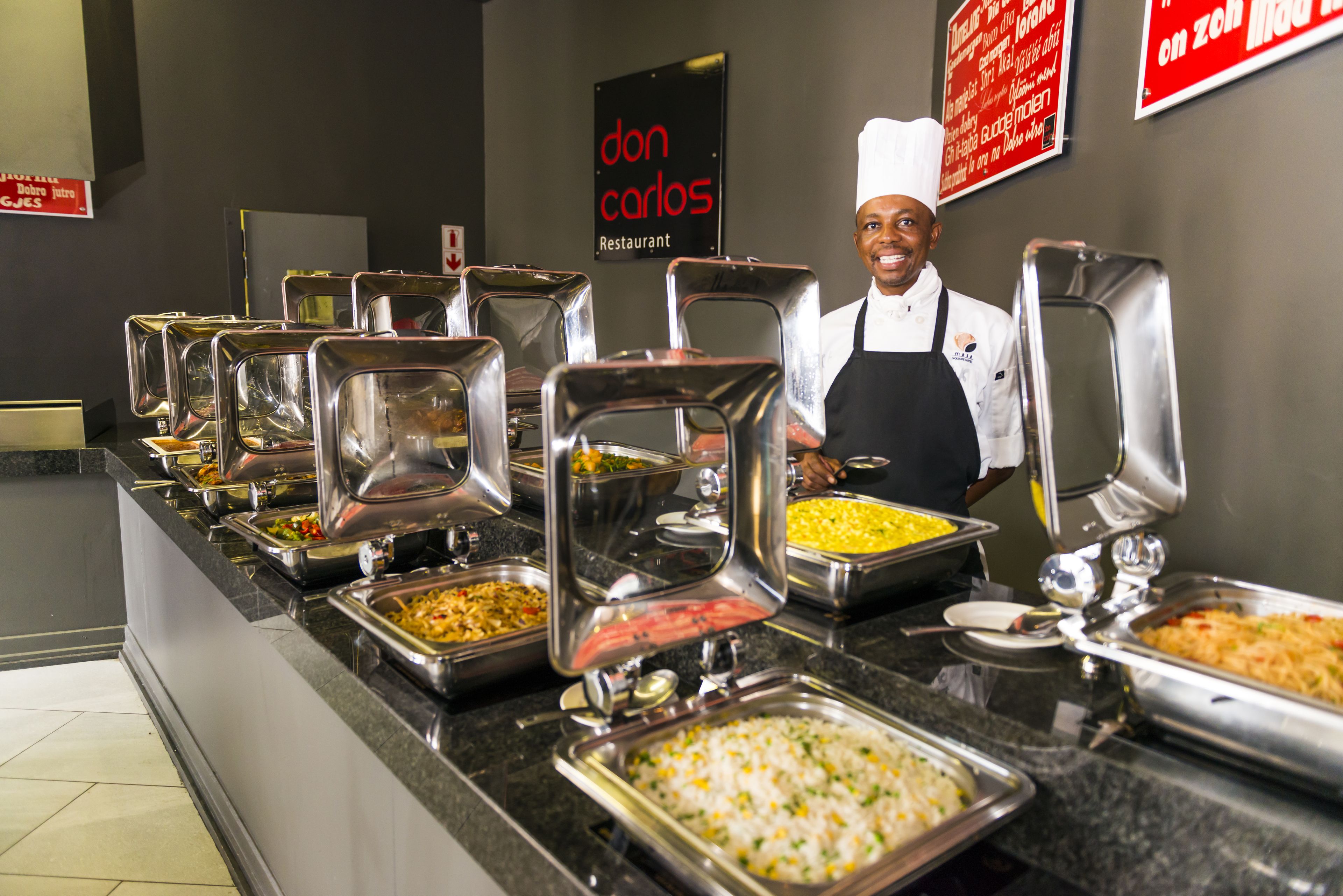 A buffet area with various food options and a chef standing behind the counter.