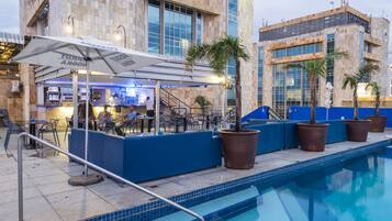 Un área de piscina con bar, asientos y plantas en macetas.