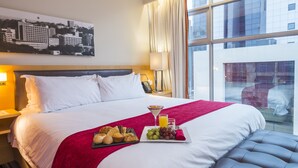A hotel room with a large bed, a cityscape view, a tray of breakfast items, and a window with curtains. - Protea Hotel by Marriott Gaborone Masa Square (Gaborone)