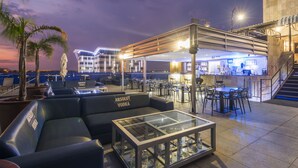 A rooftop bar with seating, a bar area, and a staircase leading to an upper level. - Protea Hotel by Marriott Gaborone Masa Square (Gaborone)