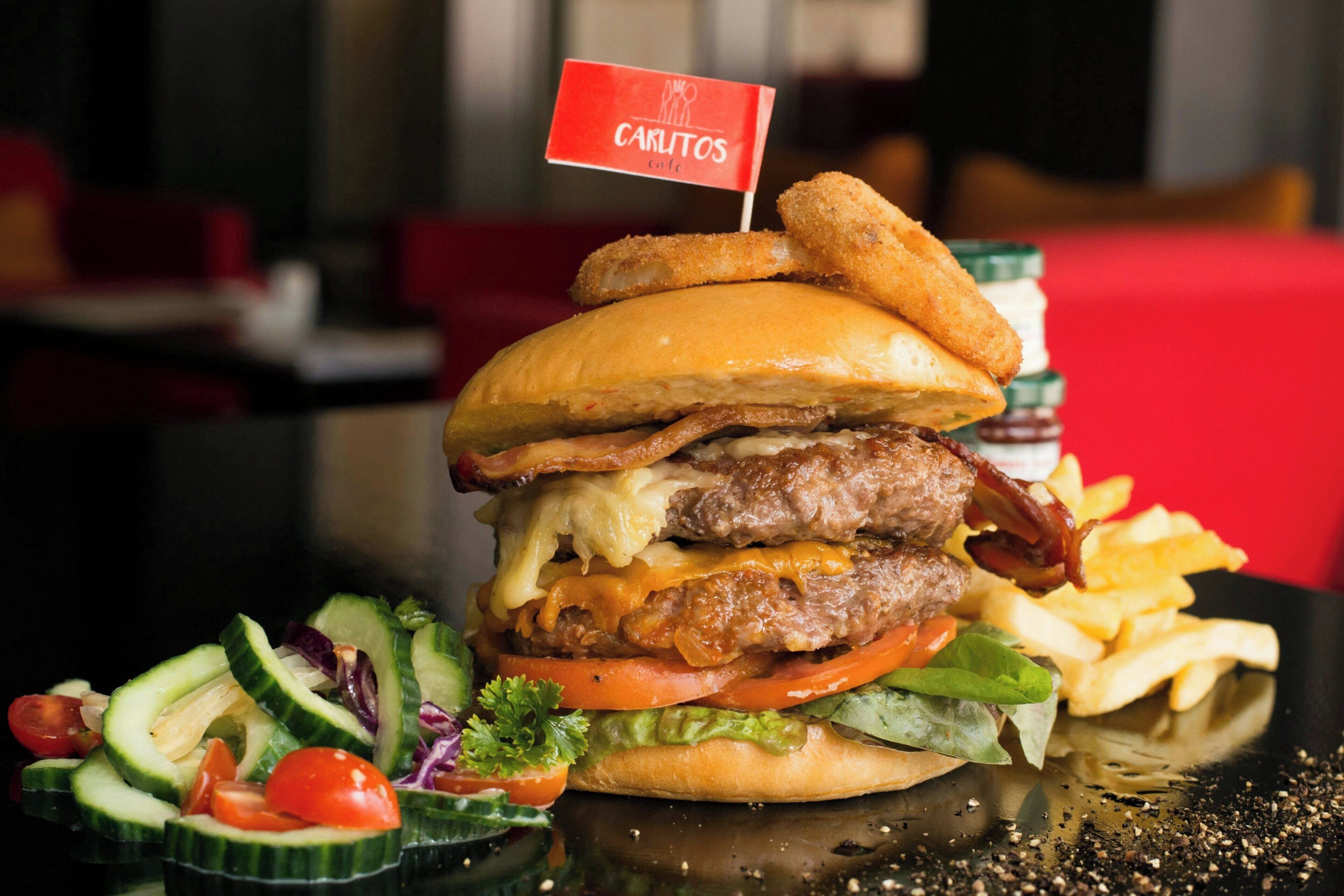 Una hamburguesa con una bandera, papas fritas y una ensalada.