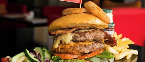 Una hamburguesa con una bandera, papas fritas y una ensalada.