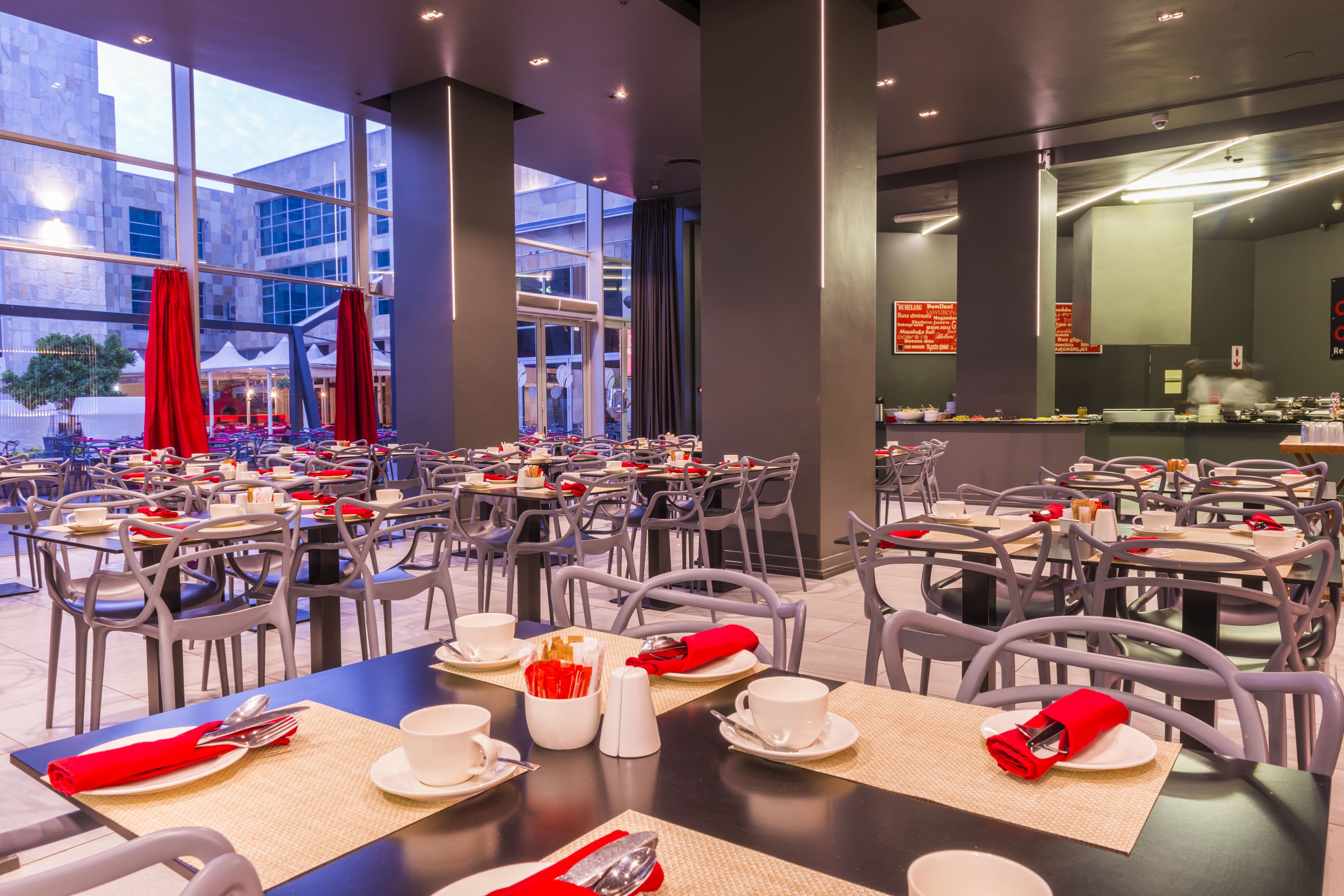 A modern dining area with tables set for breakfast, featuring white plates, cups, and cutlery.