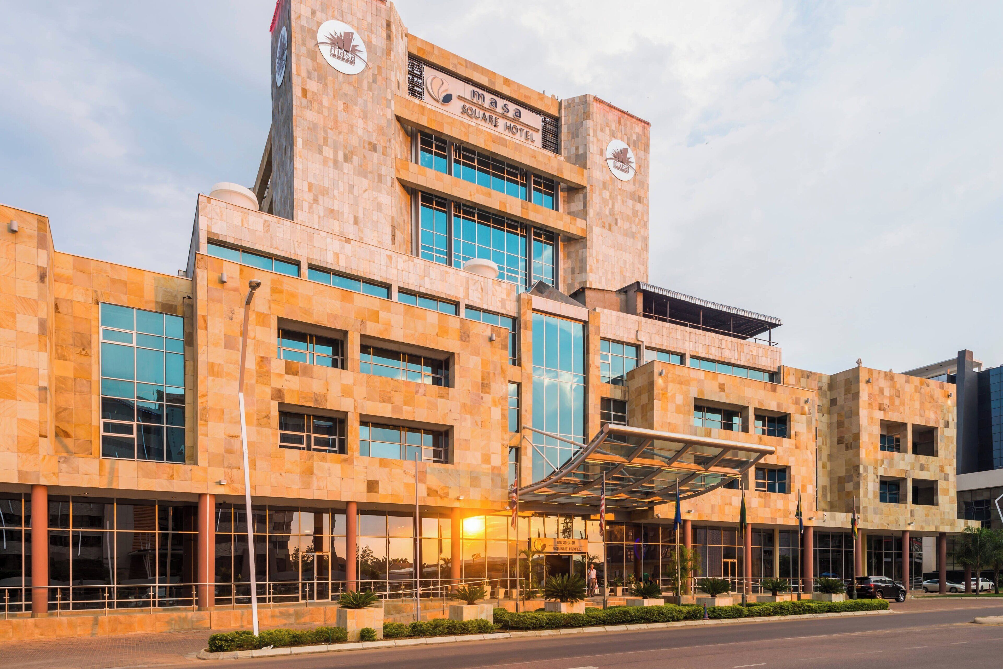Un hotel moderno con una destacada torre de reloj, amplias ventanas y un área de entrada cubierta.